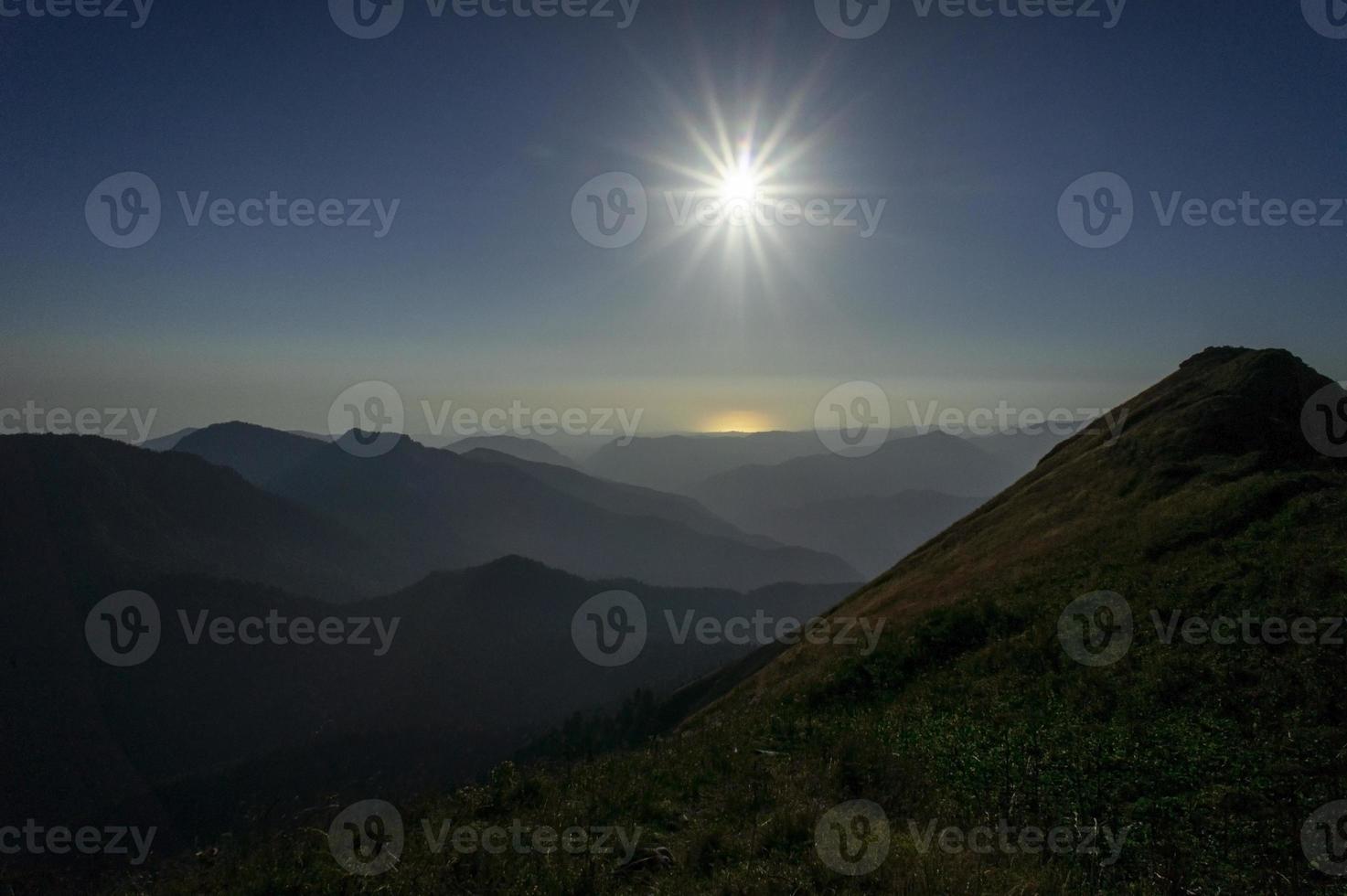 paisaje de montaña con siluetas de montañas y el sol poniente. hora dorada foto