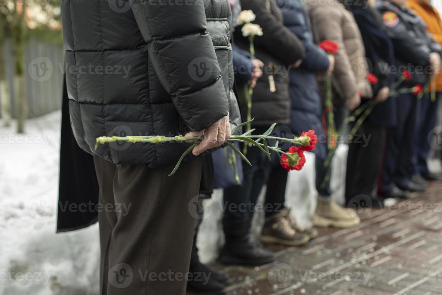 Flowers in old man's hand at funeral. Details of funeral ceremony. Commemorative flowers. photo