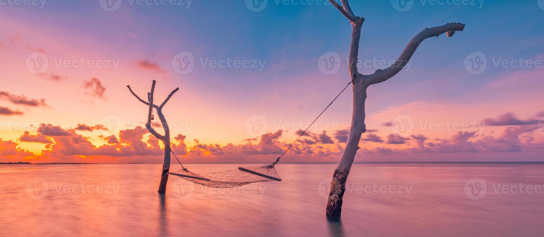 Summer holiday template. Sunset over water hammock in tropical sea lagoon. Relaxing romantic sky with colorful clouds, dream vacation, love romance couple concept. Cast away, amazing nature landscape photo