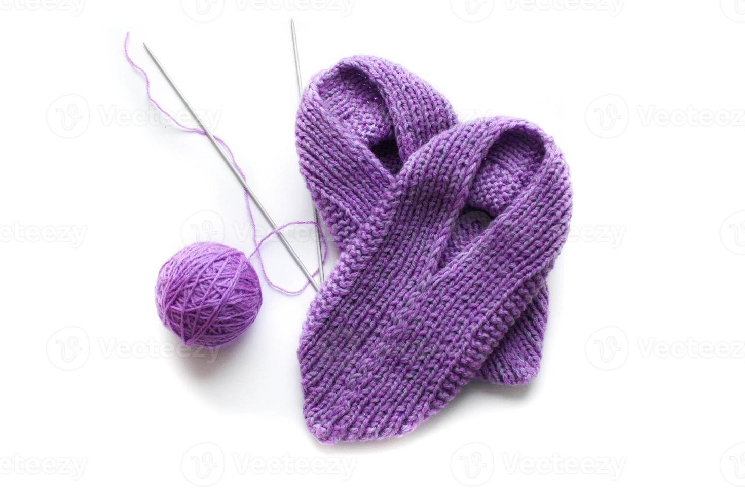 Handmade knitted pink slippers with knitting needles and ball of yarn. On white background you can easily place text or change the background photo