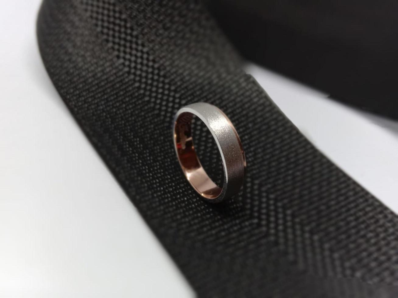 a wedding ring and engagement ring with rose gold material with a white variation of doff which is placed on a black bag strap photo