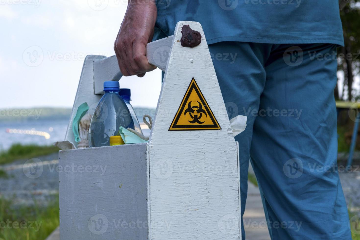 señal de peligro biológico en la caja con muestras de agua del lago en manos de un empleado foto
