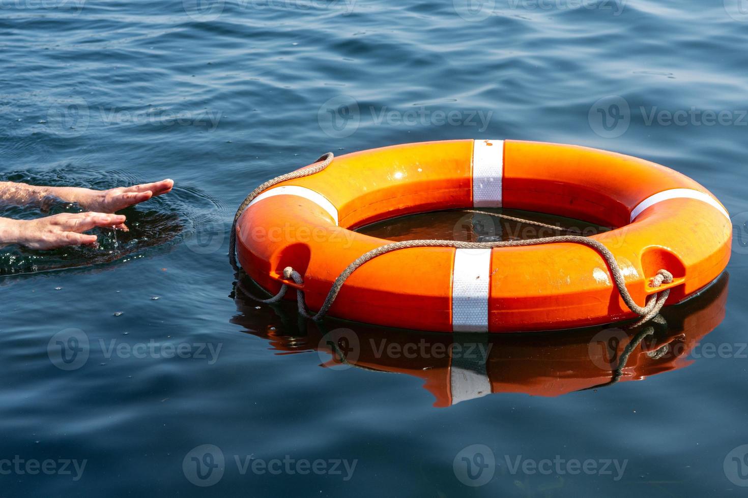 las manos del hombre alcanzan el aro salvavidas en el agua. el concepto de salvar el ahogamiento foto