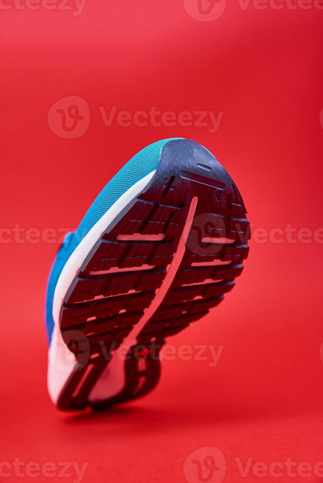 Blue running sneaker on red background, close up photo
