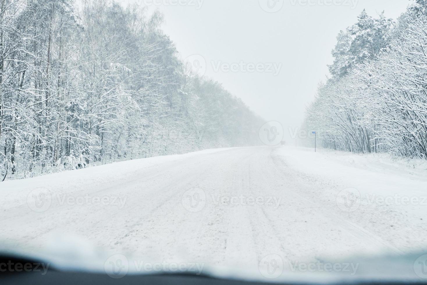 Snowy road in winter forest with moving car photo