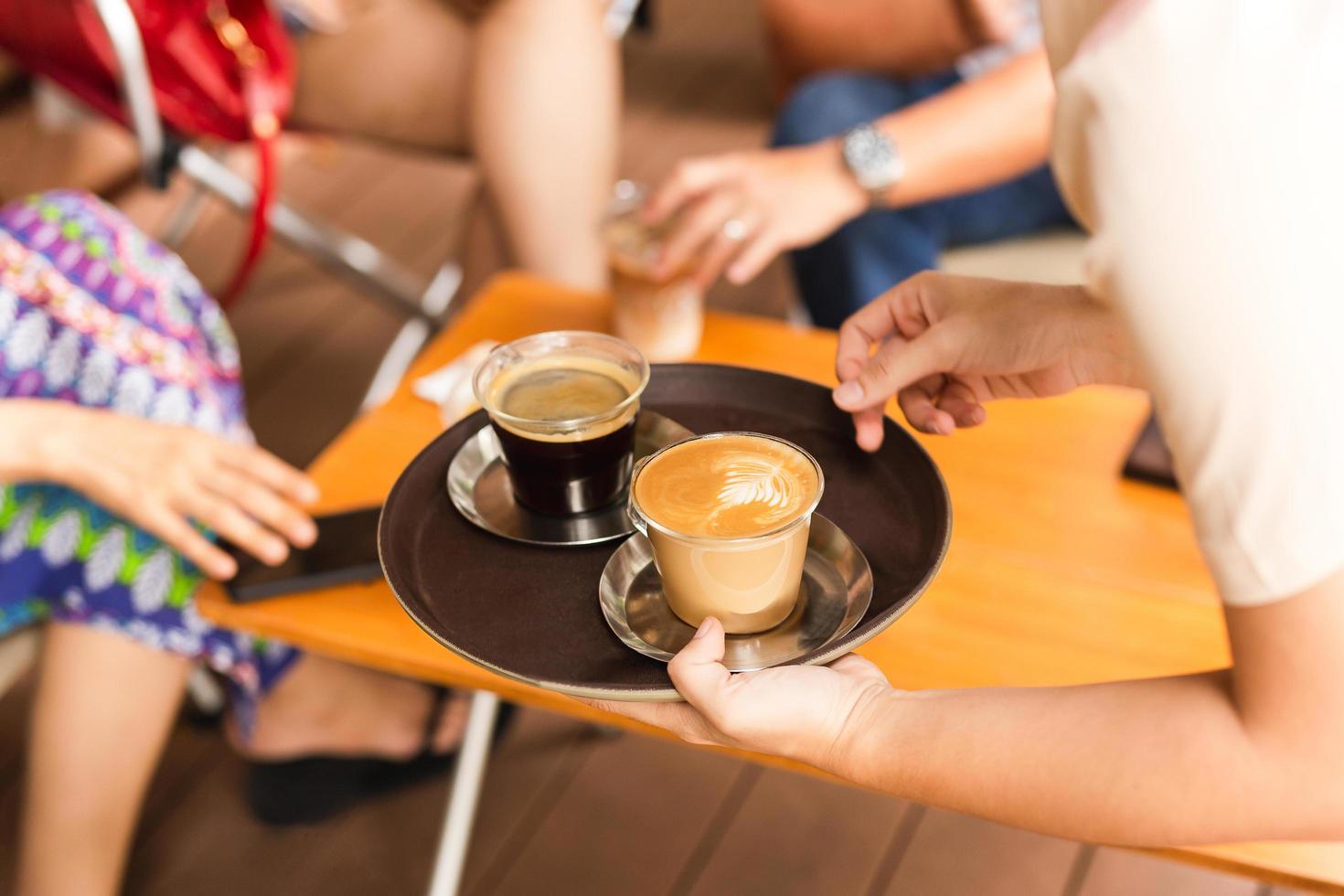 camarera sirviendo al cliente un café caliente en la cafetería. foto