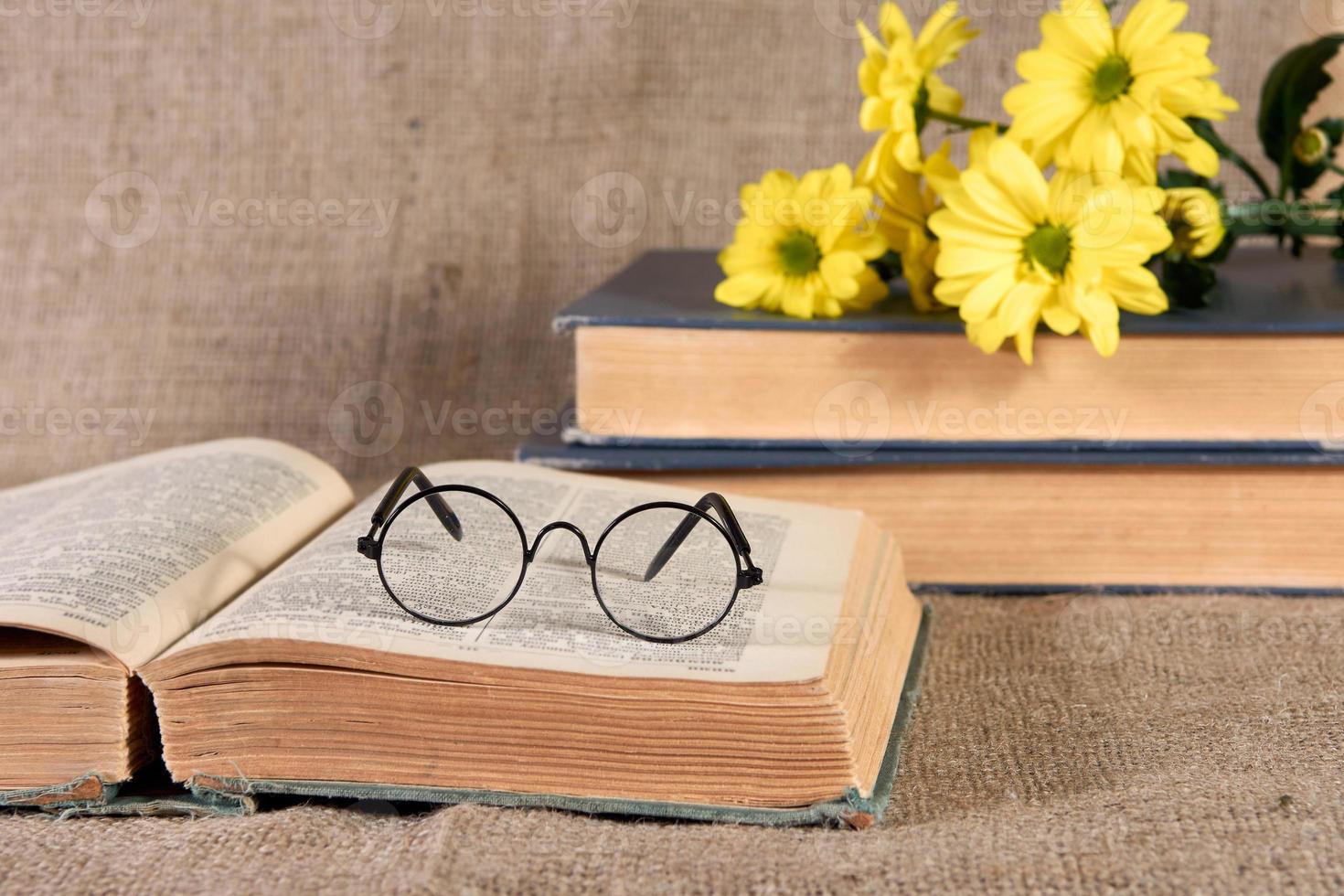 Yellow chrysanthemums, an old book, and glasses on the table. photo