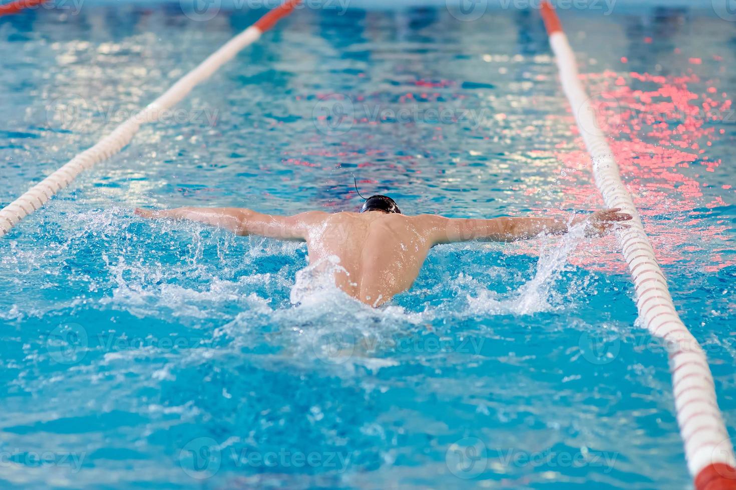 a swimmer waves his arms while performing a butterfly at a training session in the pool, blurred focus photo