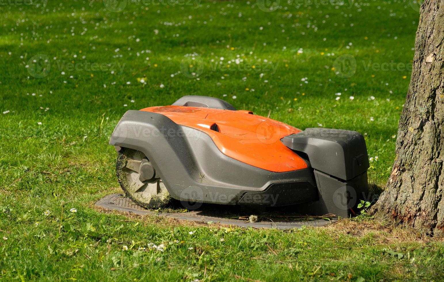 Robotic Lawn Mower on green grass background.Automatic robot lawnmower in modern garden.Green grass trimming with lawn mower. Close-up view of the lawn mower dirty blade after mowing the lawn. photo