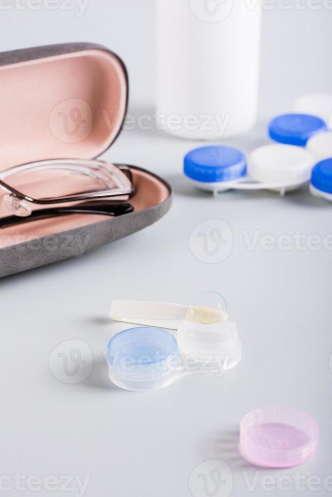 Contact lens on an open storage container on the background of a case with glasses. Vertical view photo