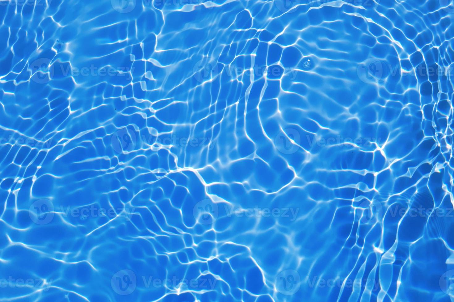 Defocus blurred transparent blue colored clear calm water surface texture with splash, bubble. Shining blue water ripple background. Surface of water in swimming pool. Blue bubble water shining. photo