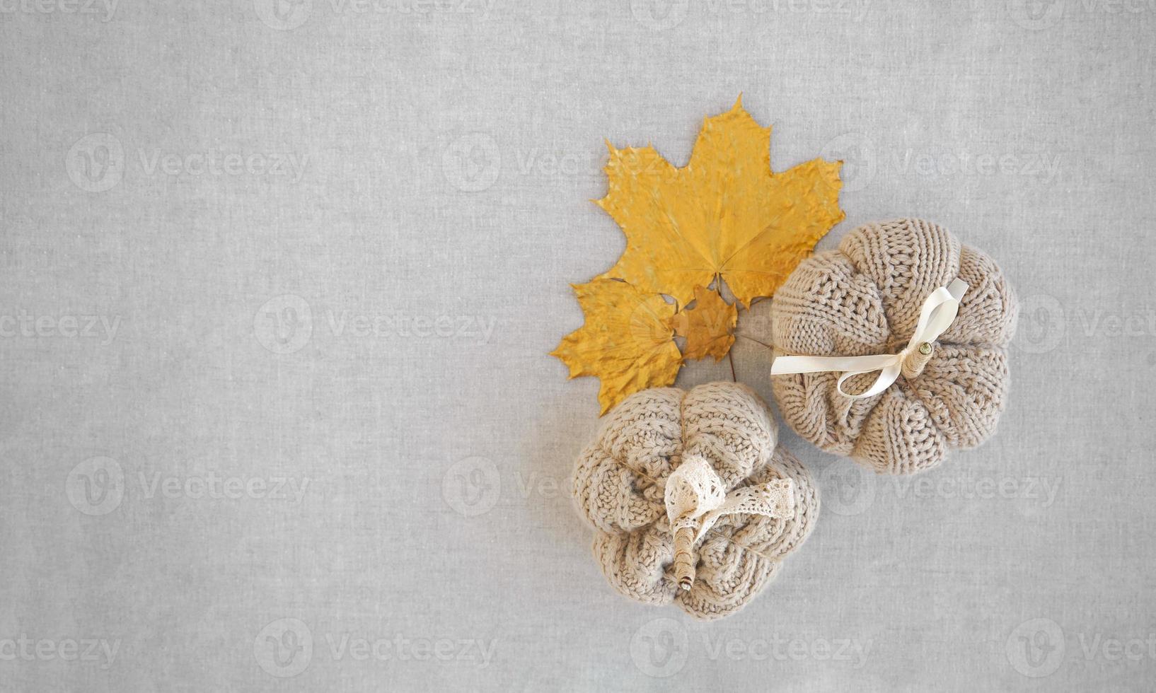 Hobby background with handmade knit pumpkins and golden maple leaves. DIY, craft decoration for fall and winter holidays. Flat lay, top view photo