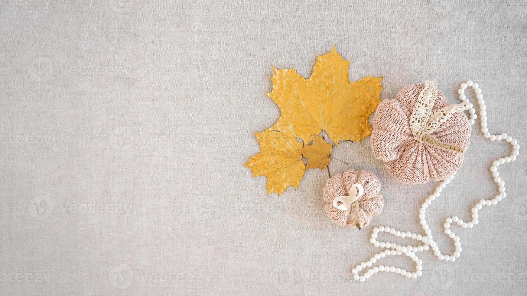 Hobby background with handmade knit pumpkins and golden maple leaves. DIY, craft decoration for fall and winter holidays. Flat lay, top view photo