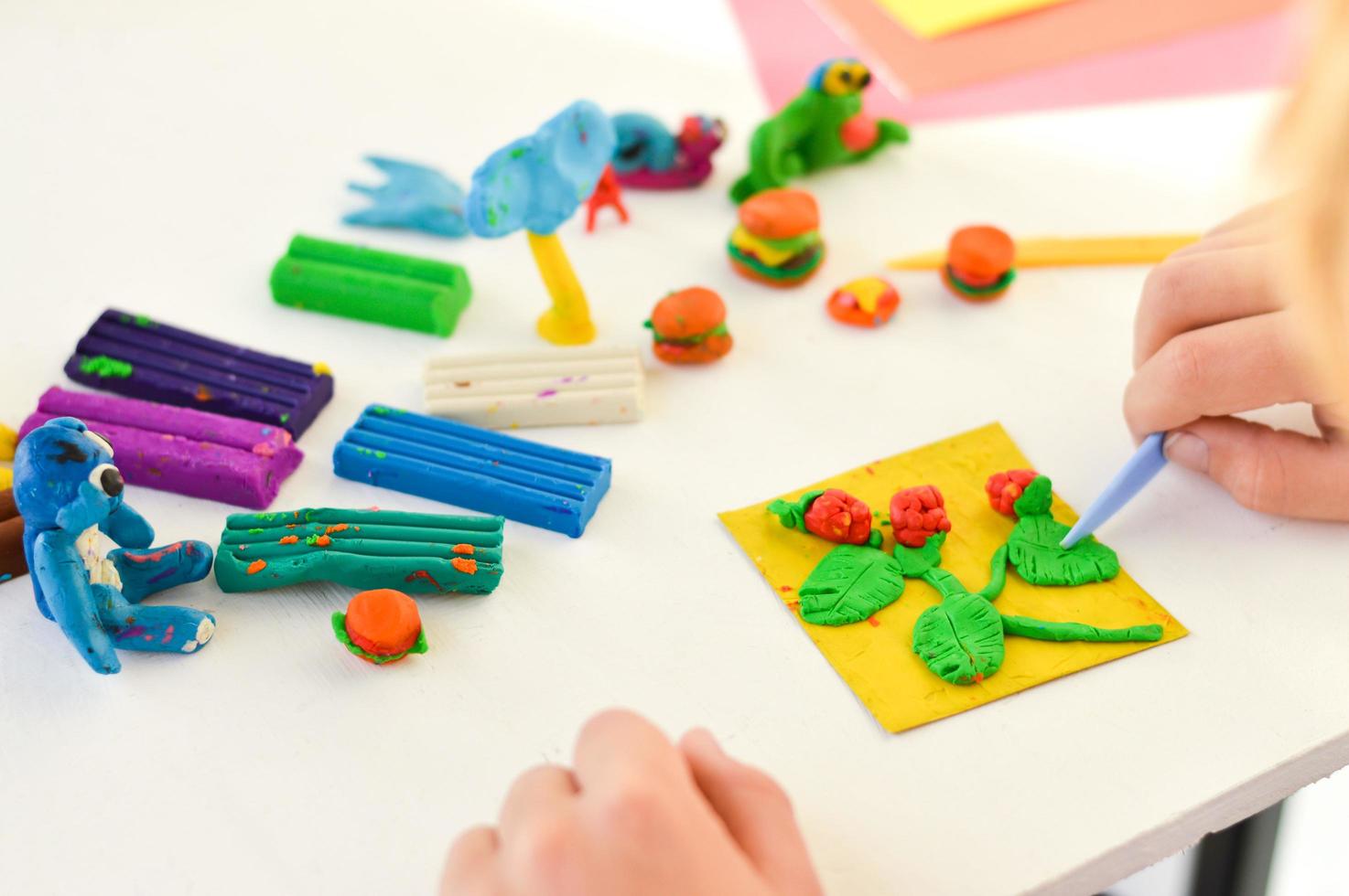 A close-up of hands with plasticine, children's crafts and an application on the theme of harvest. photo