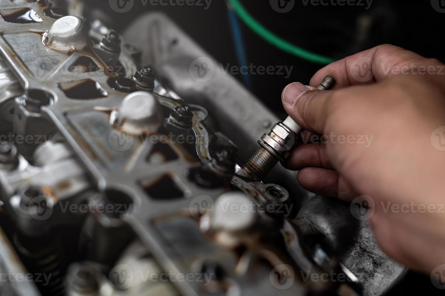 Old Car spark plug in a hand of Technician remove and change in engine room blur background service concept photo