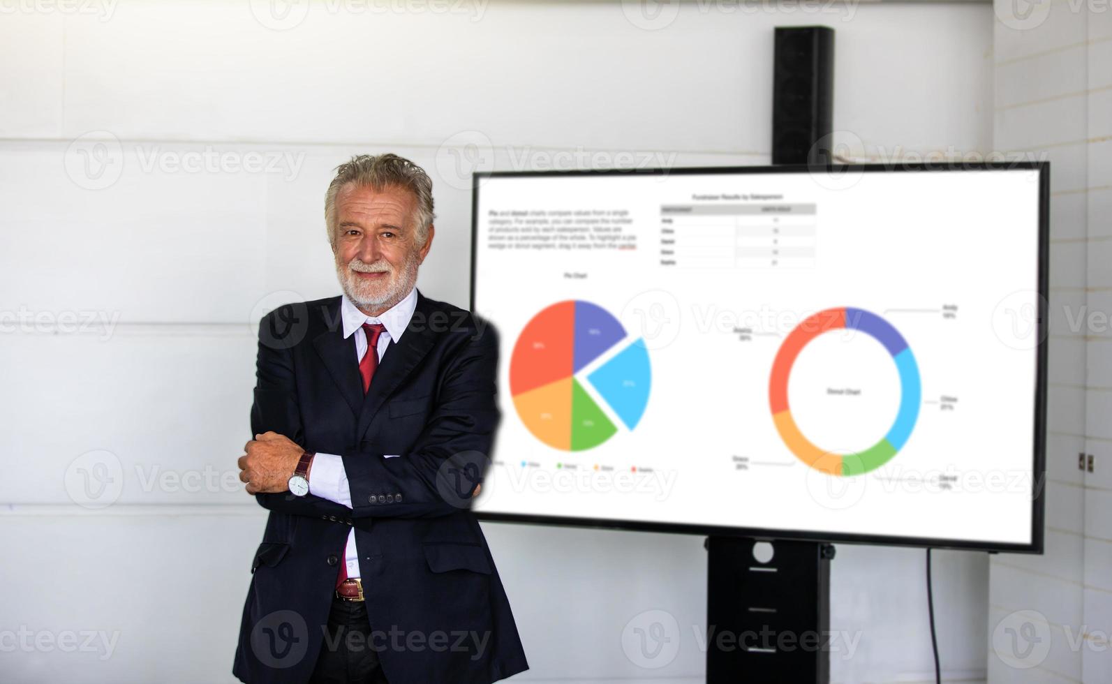 elderly  business man standing with a confident smile and crossed arms in front of the conference room preparing to present his work. photo