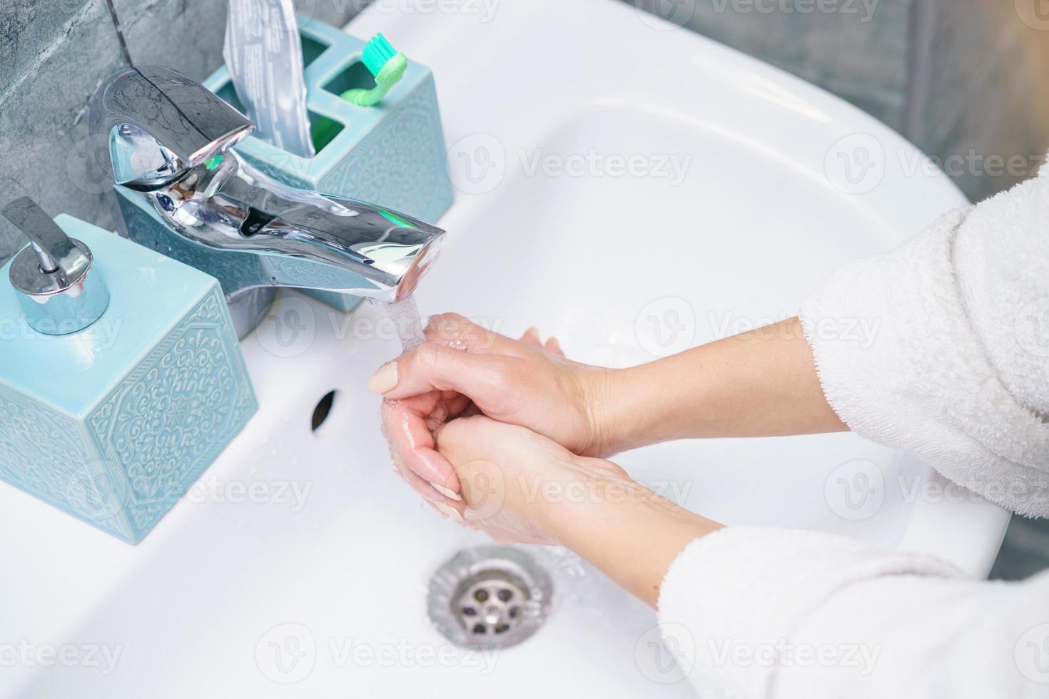 mujer se lava la mano en el lavabo del baño, sin rostro foto