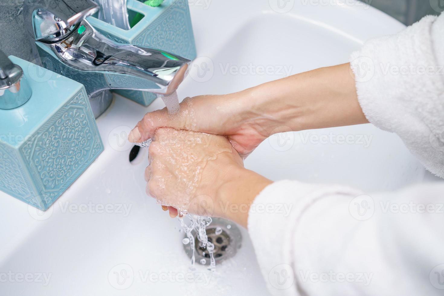 Woman washes her hand in the bathroom sink, without a face photo