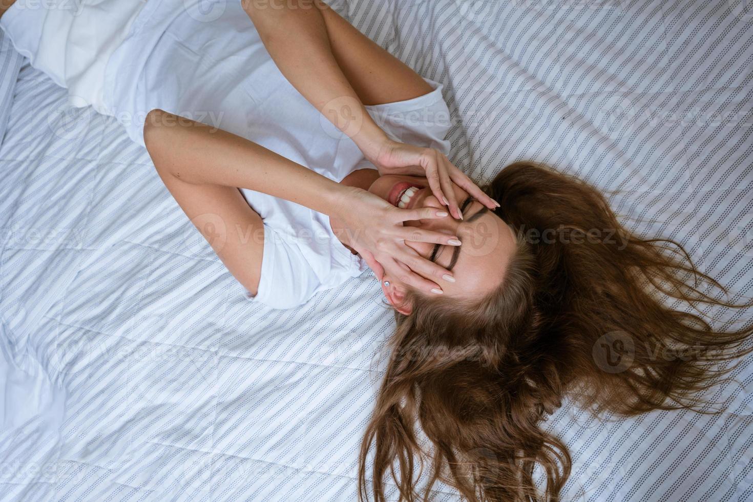 Young woman wakes up after a good night's sleep in photo