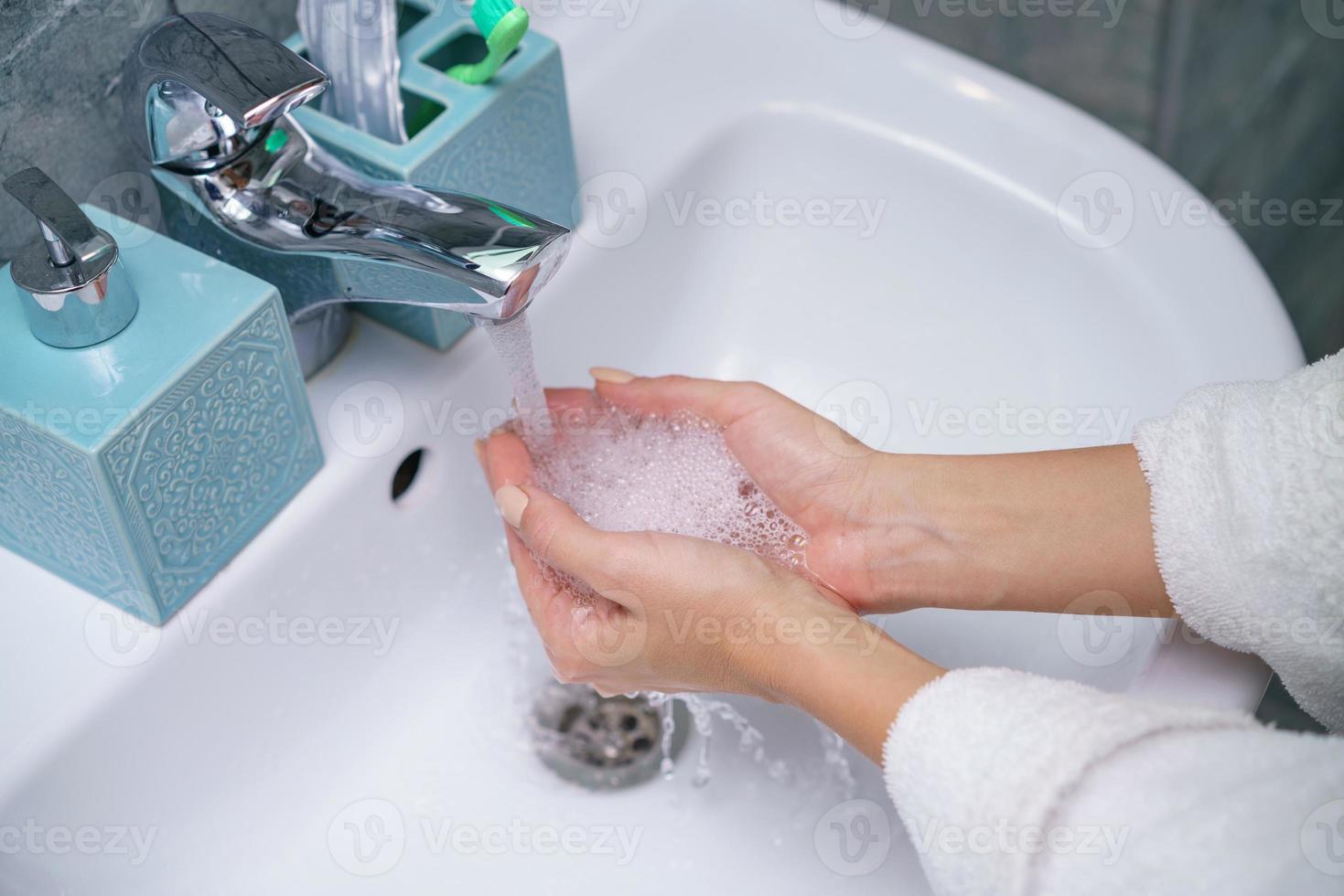 Woman washes her hand in the bathroom sink, without a face photo