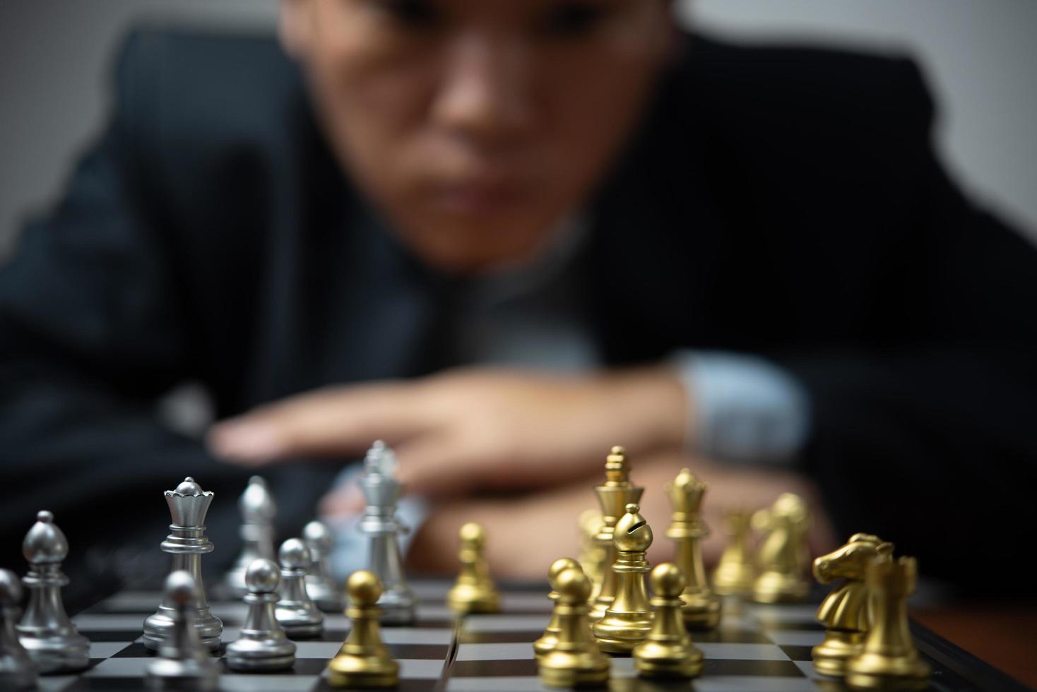 Strategic planning and goals success business idea. Businessman looking at chess at the board. photo