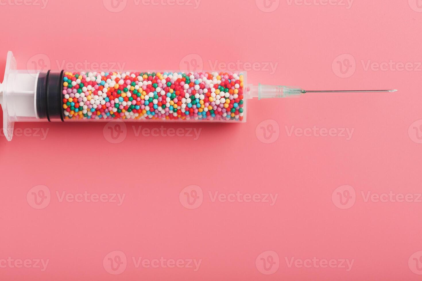 Syringe filled with colorful nano balls on a pink background. 13150430