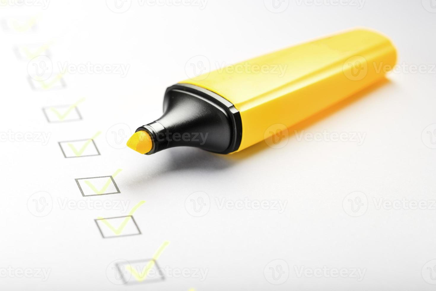marcador amarillo con marcadores en la hoja de lista de verificación. foto