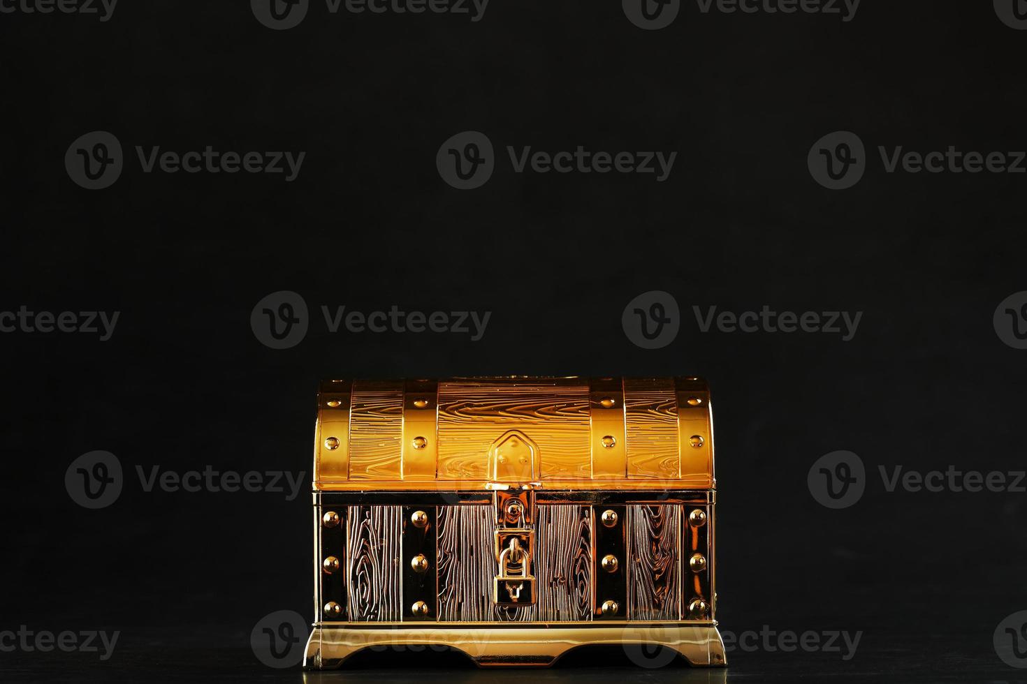 Gold treasure chest on a black textured background. photo