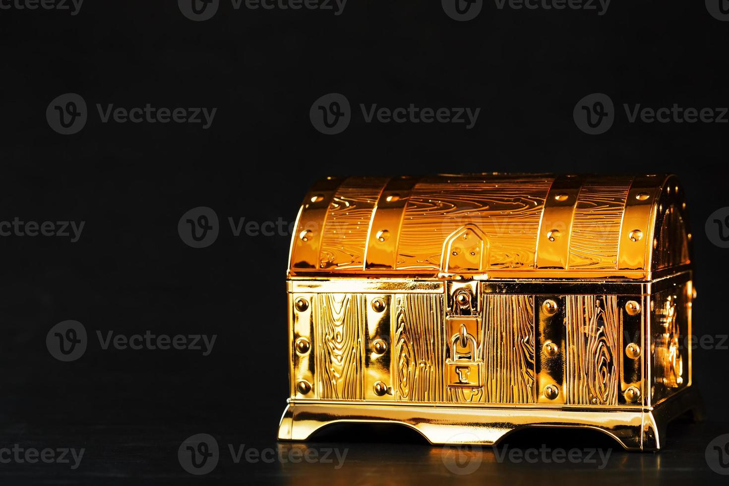 Gold treasure chest on a black textured background. photo