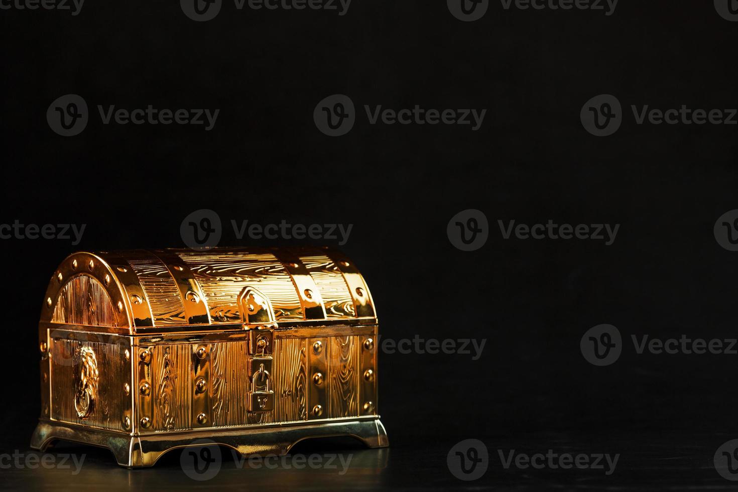 A chest made of gold with jewels on a black background. photo