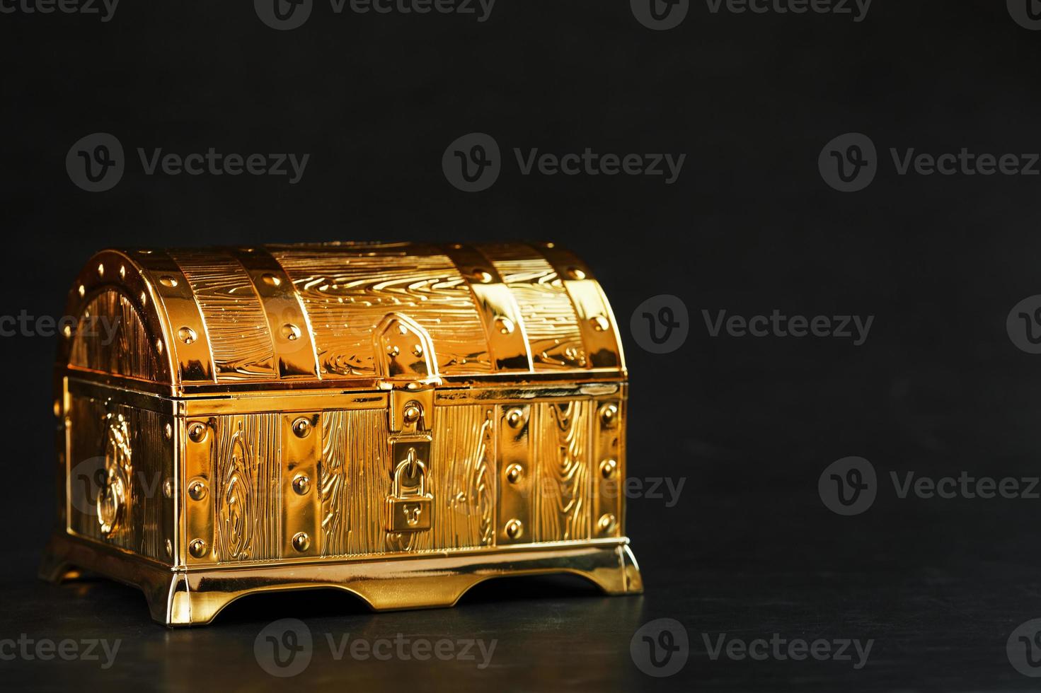 Gold treasure chest on a black textured background. photo