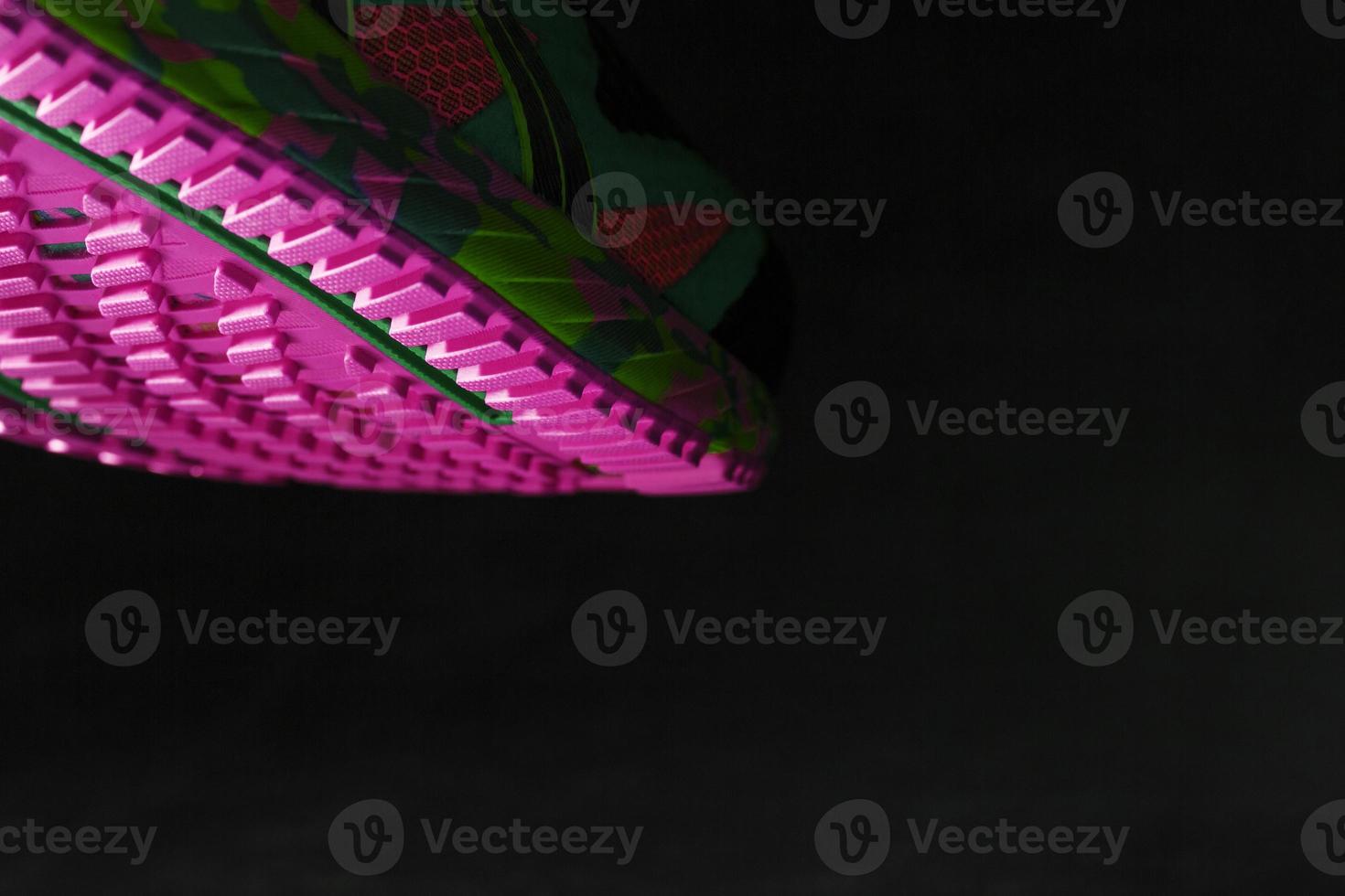 Textured pink sole of sports running shoes on a black background. photo