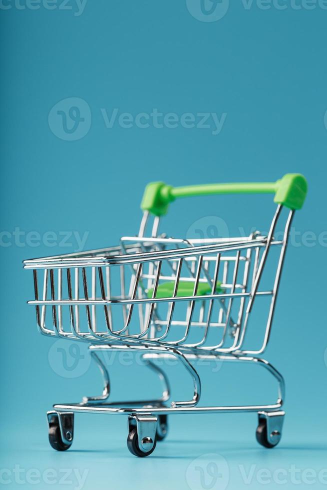 Empty shopping cart for goods from the supermarket on a blue background. photo