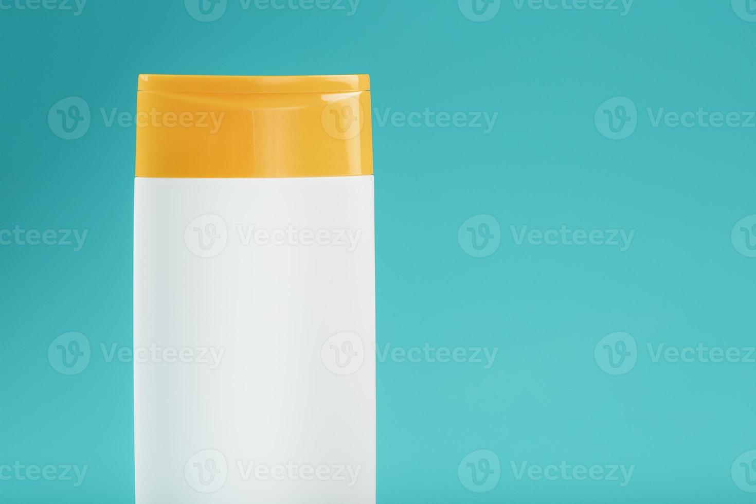 White plastic bottle with yellow cap with shampoo gel on blue background. photo