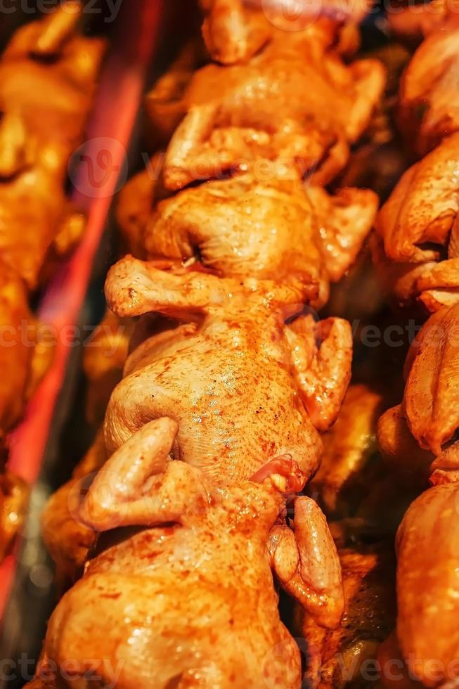 pollo a la parrilla jugoso y sabroso con una corteza dorada en un pincho en una fila. foto