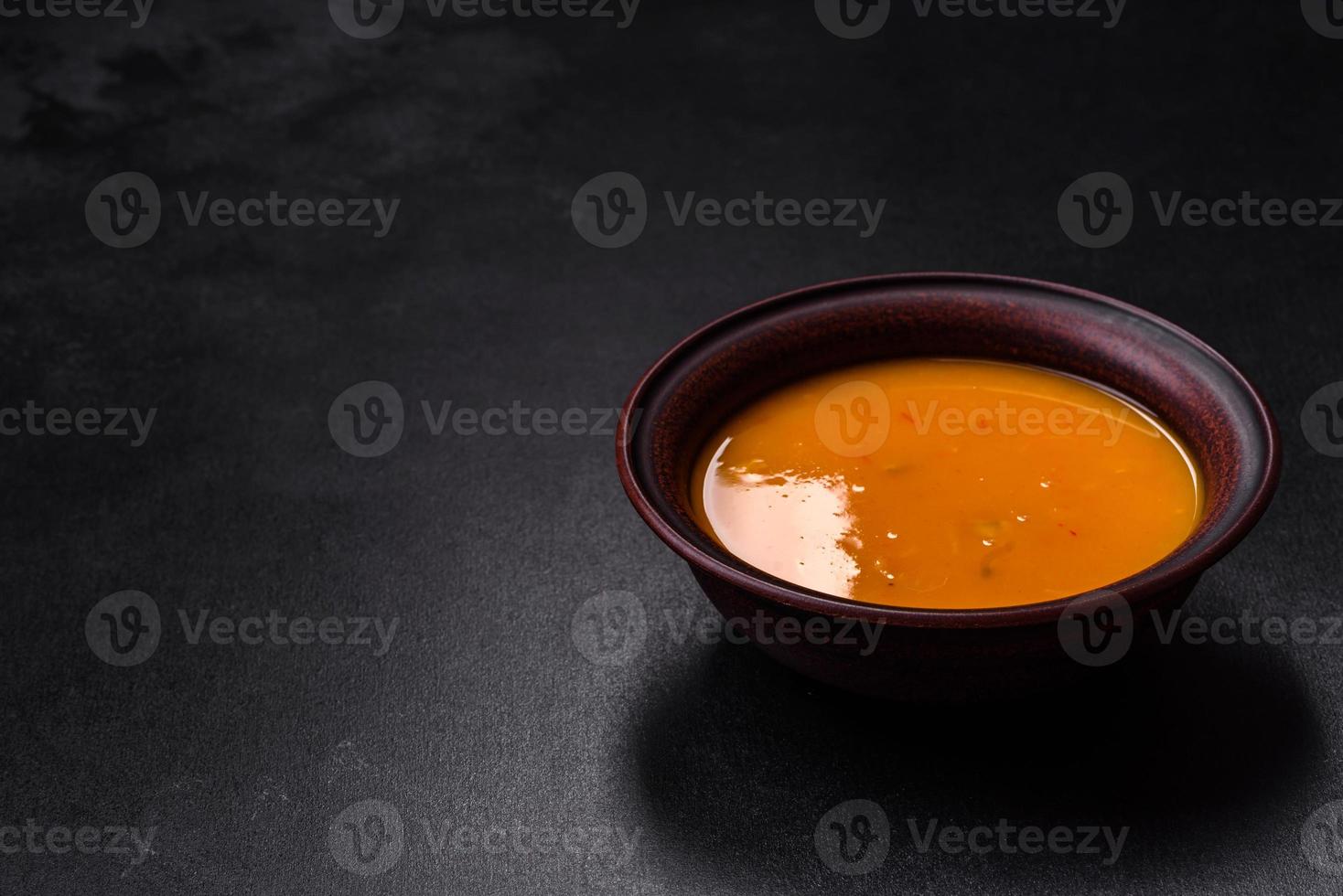 Delicious hot pumpkin and carrot soup puree with spices and herbs photo