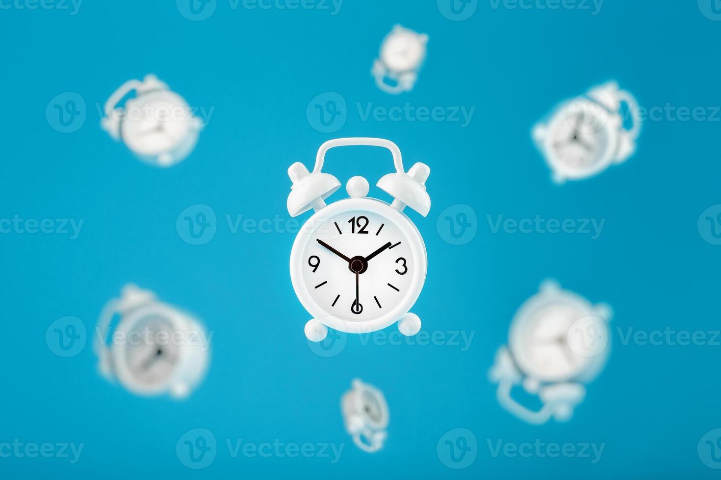 White retro alarm clocks in flight in the center, isolated on a blue