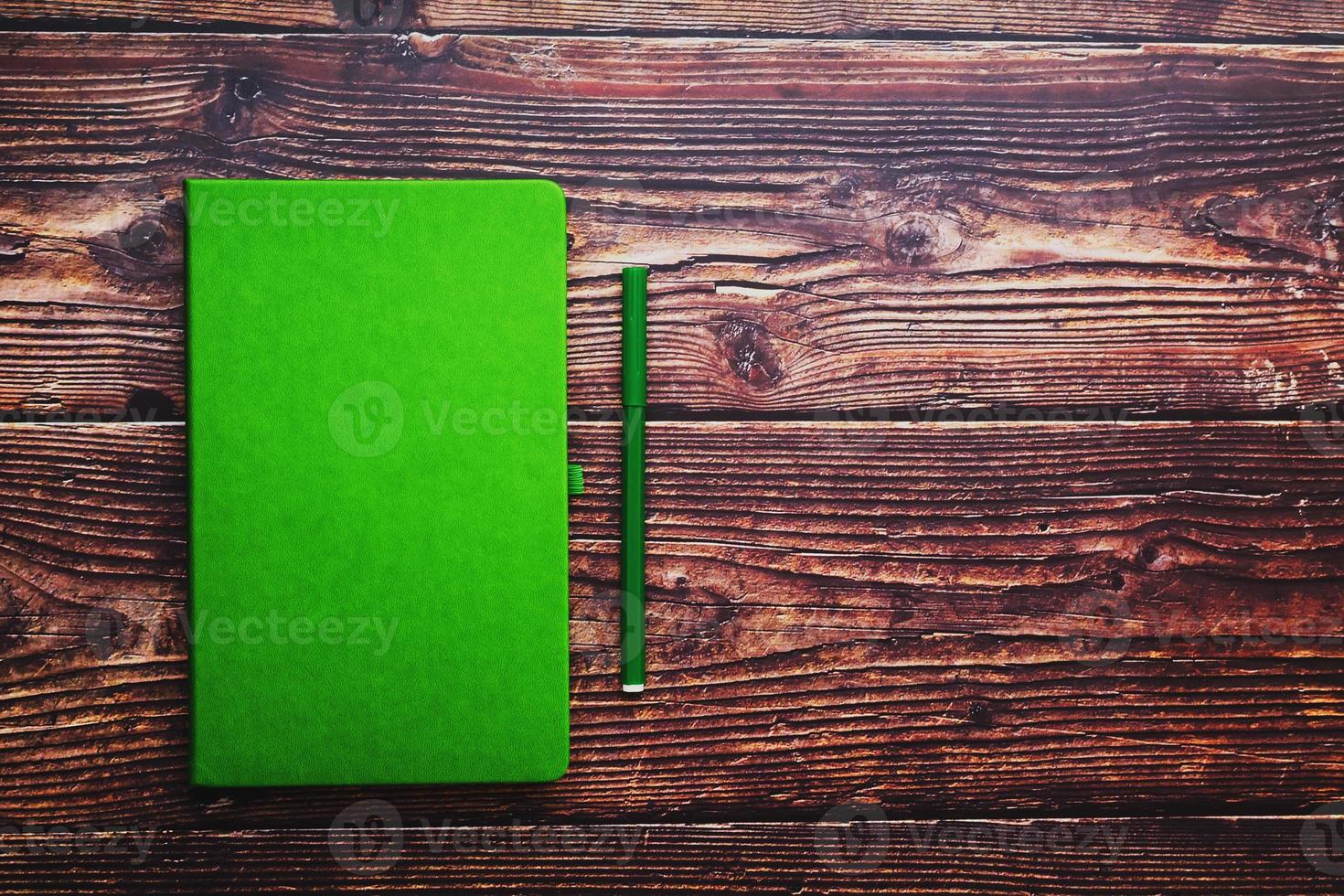 Green Notepad with a felt-tip pen on a brown wooden table, top view. photo