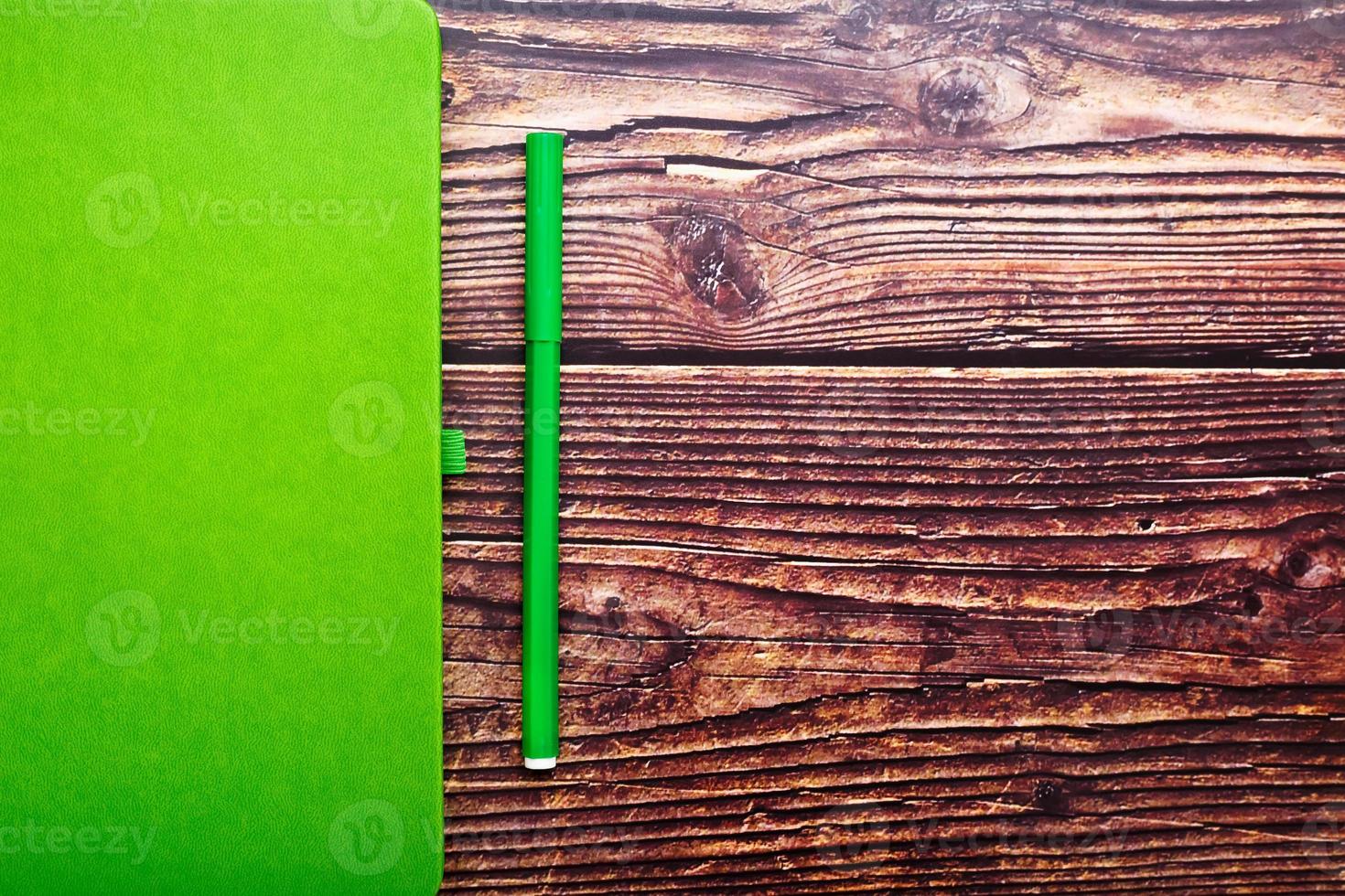 Green Notepad with a felt-tip pen on a brown wooden table, top view. photo