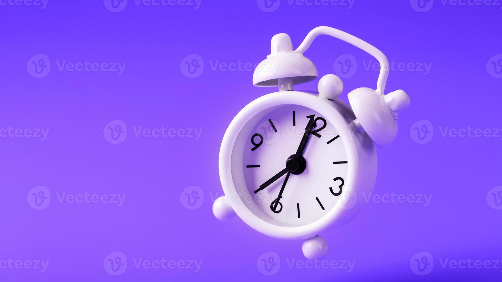 White retro style alarm clock in levitation isolated on purple background. photo