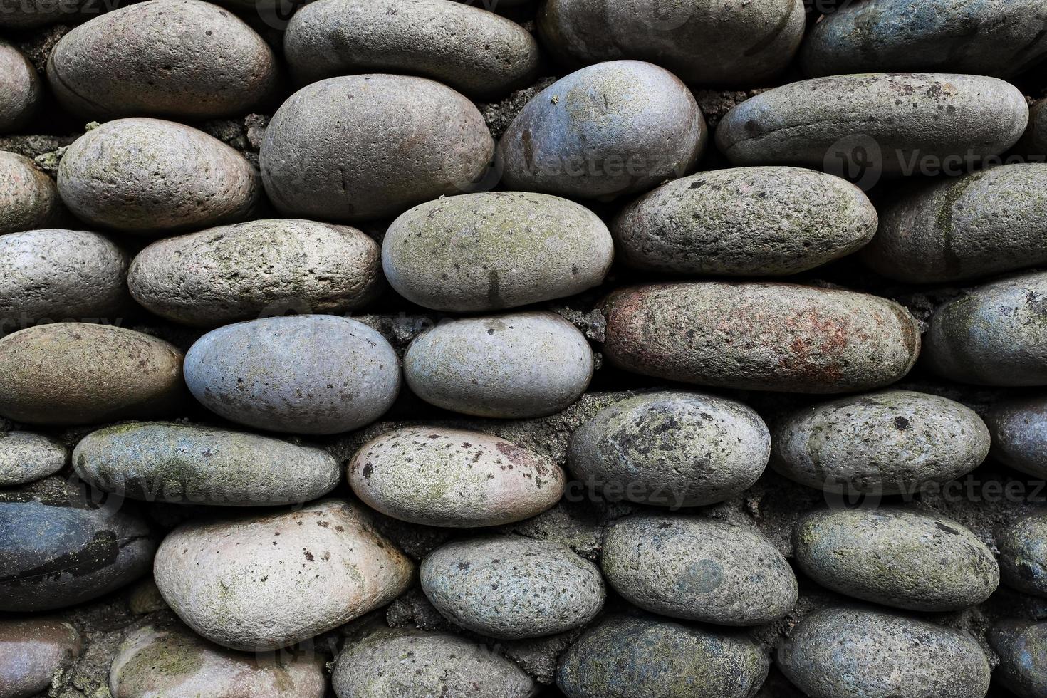 la textura de la pared de piedra, mampostería de piedras ovaladas naturales. foto