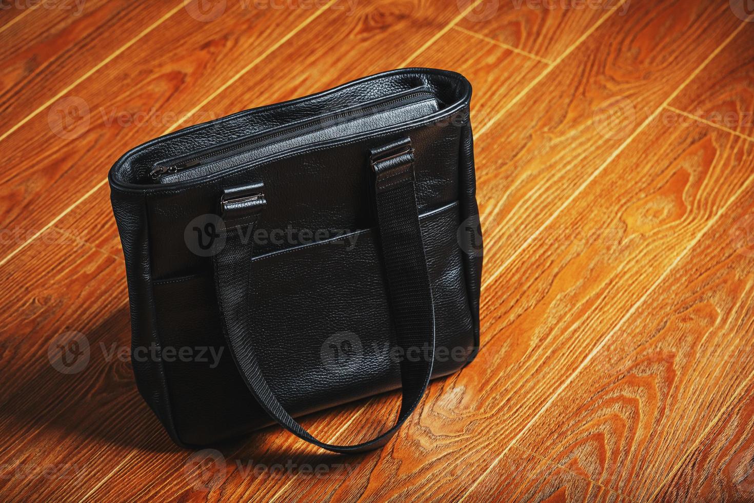Handmade black leather bag on a wooden background, made of natural material. photo