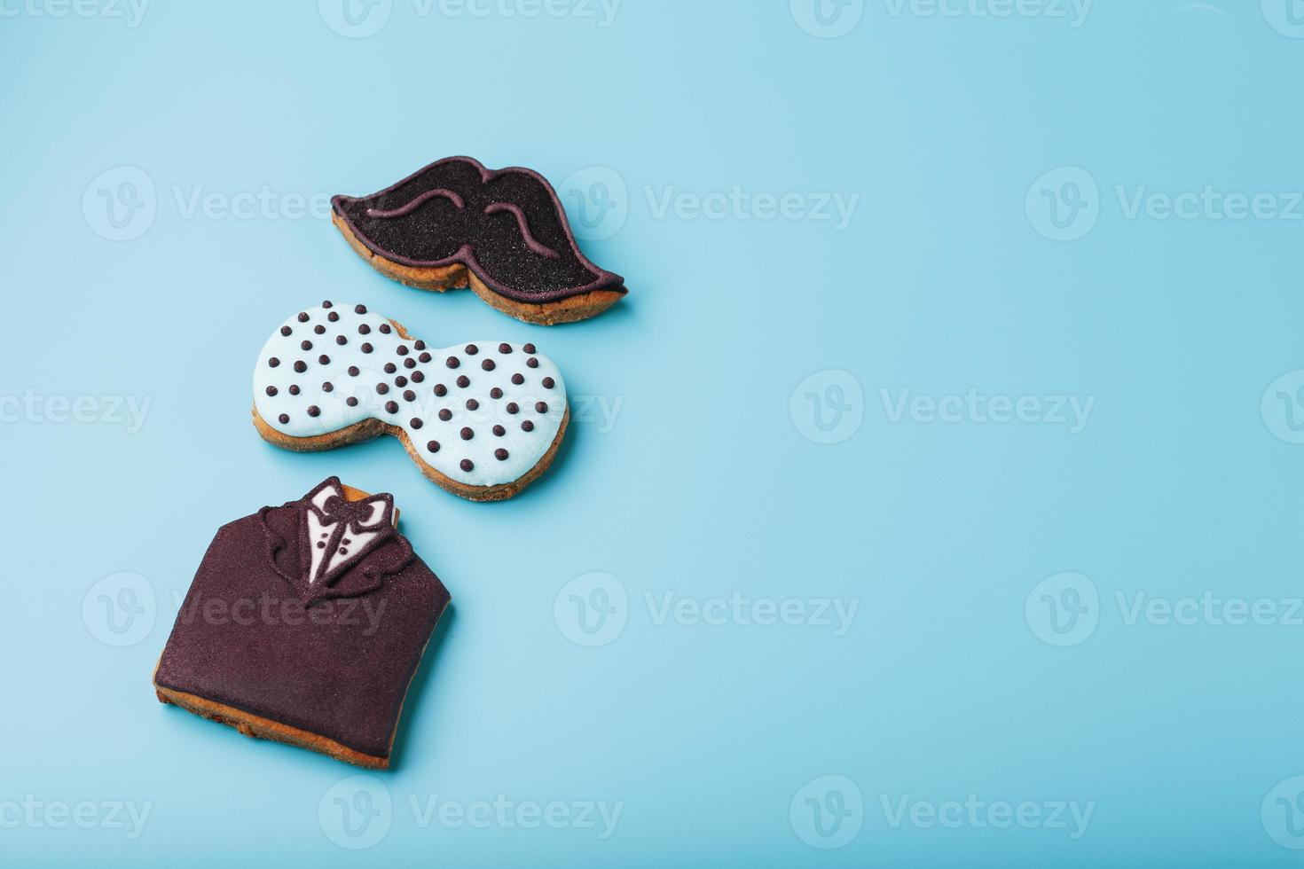 Glazed gingerbread in the form of a mustache, butterfly and tuxedo, men's set on a blue background. Handmade cookies. photo