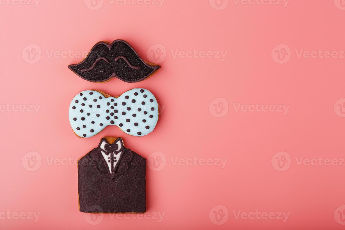 Glazed gingerbread in the form of a mustache, butterfly and tuxedo, stars men's set on a pink background. Handmade cookies. photo