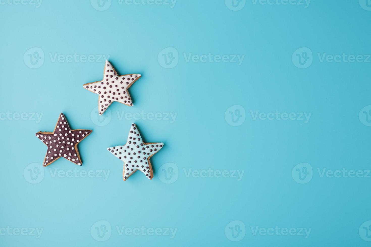 Close-up of three homemade glazed gingerbread cookies made in the form of stars on a blue background. Handmade cookies. Free space. photo