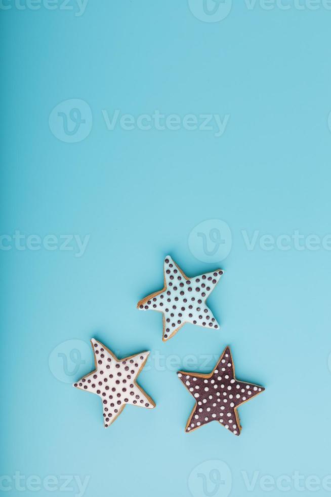 Close-up of three homemade glazed gingerbread cookies made in the form of stars on a blue background. Handmade cookies. Free space. photo