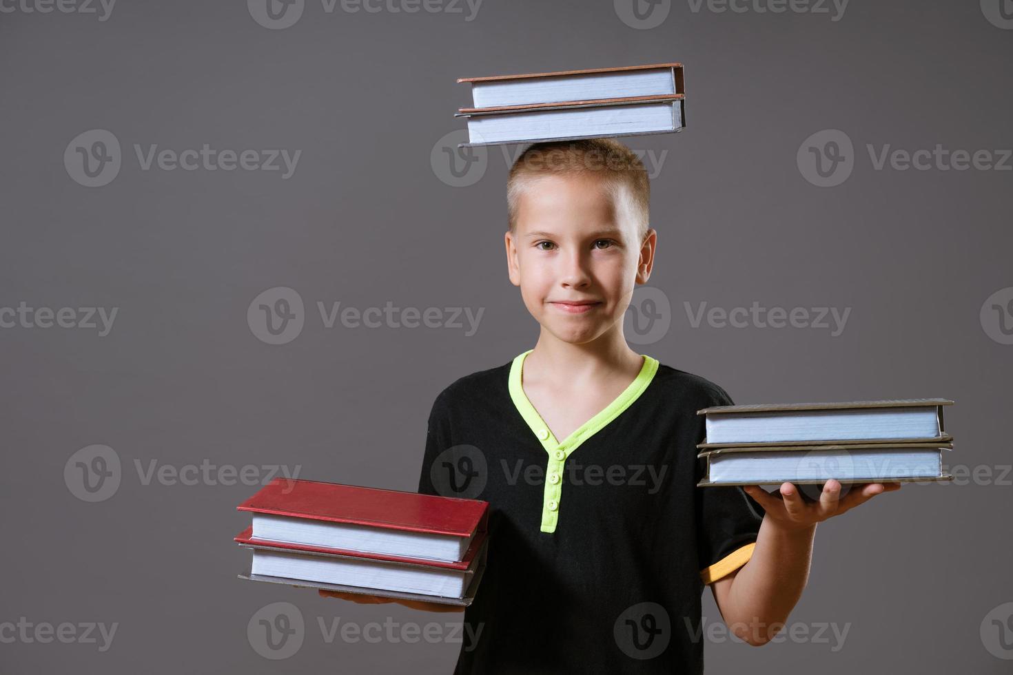 niño sostenga las pilas de libros en sus manos y en su cabeza foto