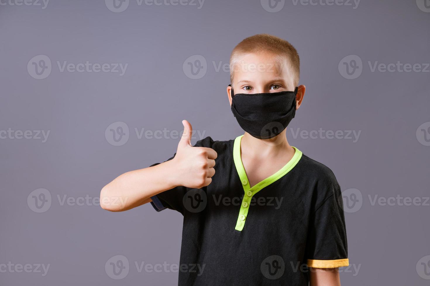 Portrait of a guy in a black mask shows a hand gesture that everything is ok photo