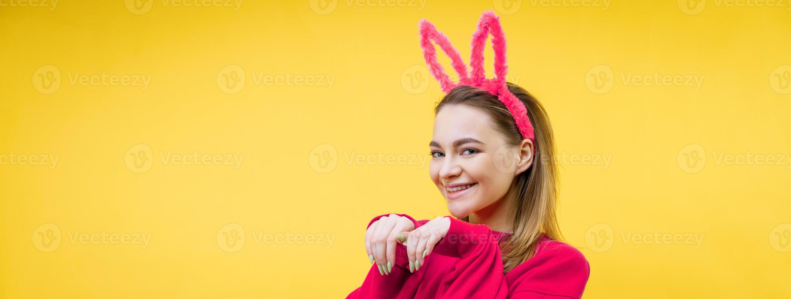 mujer joven en orejas de conejo sobre un fondo amarillo foto