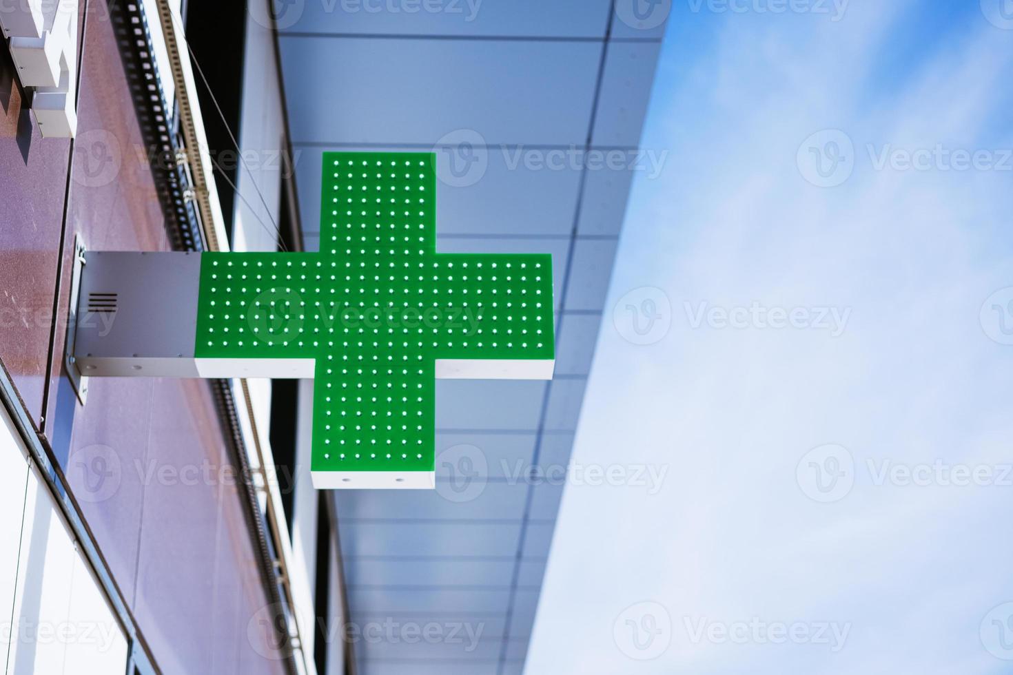 green cross on the facade of the building against the sky photo